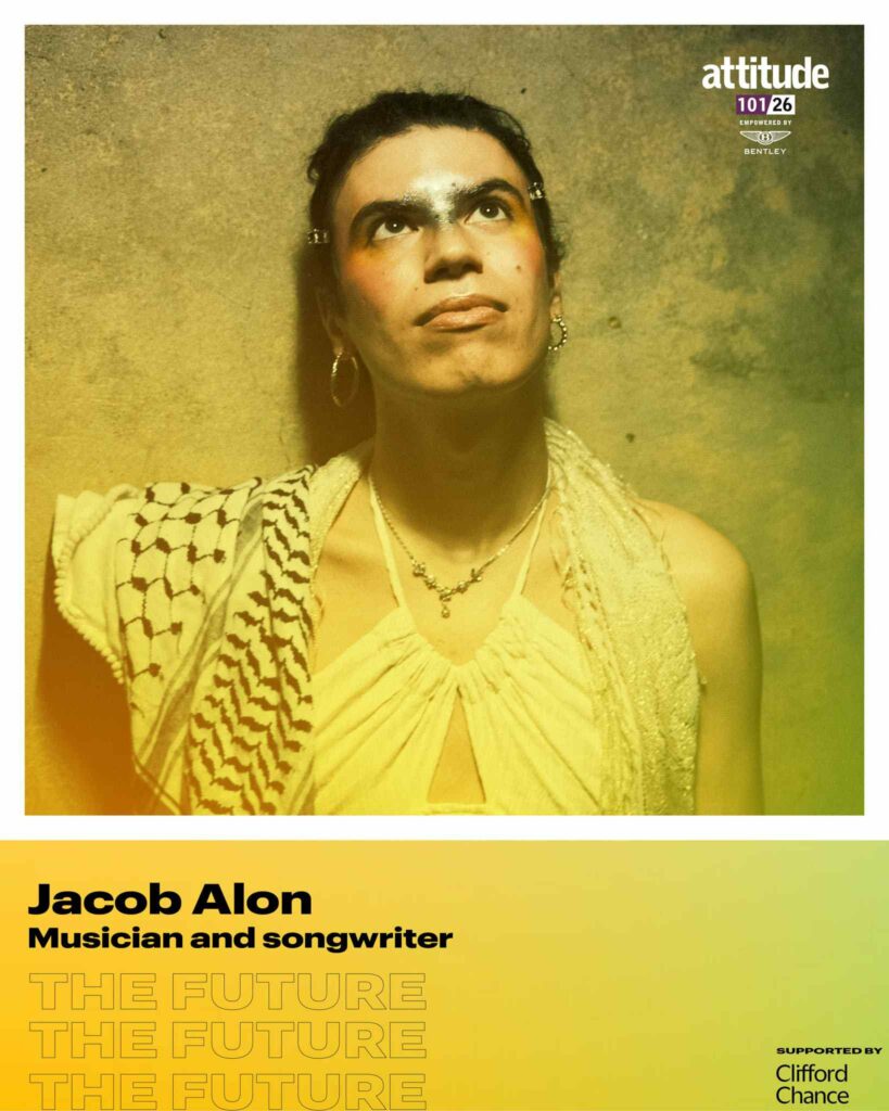 Jacob Alon wearing a sleeveless top and scarf, looking upwards against a textured wall, with the Attitude 101 logo visible in the top corner.