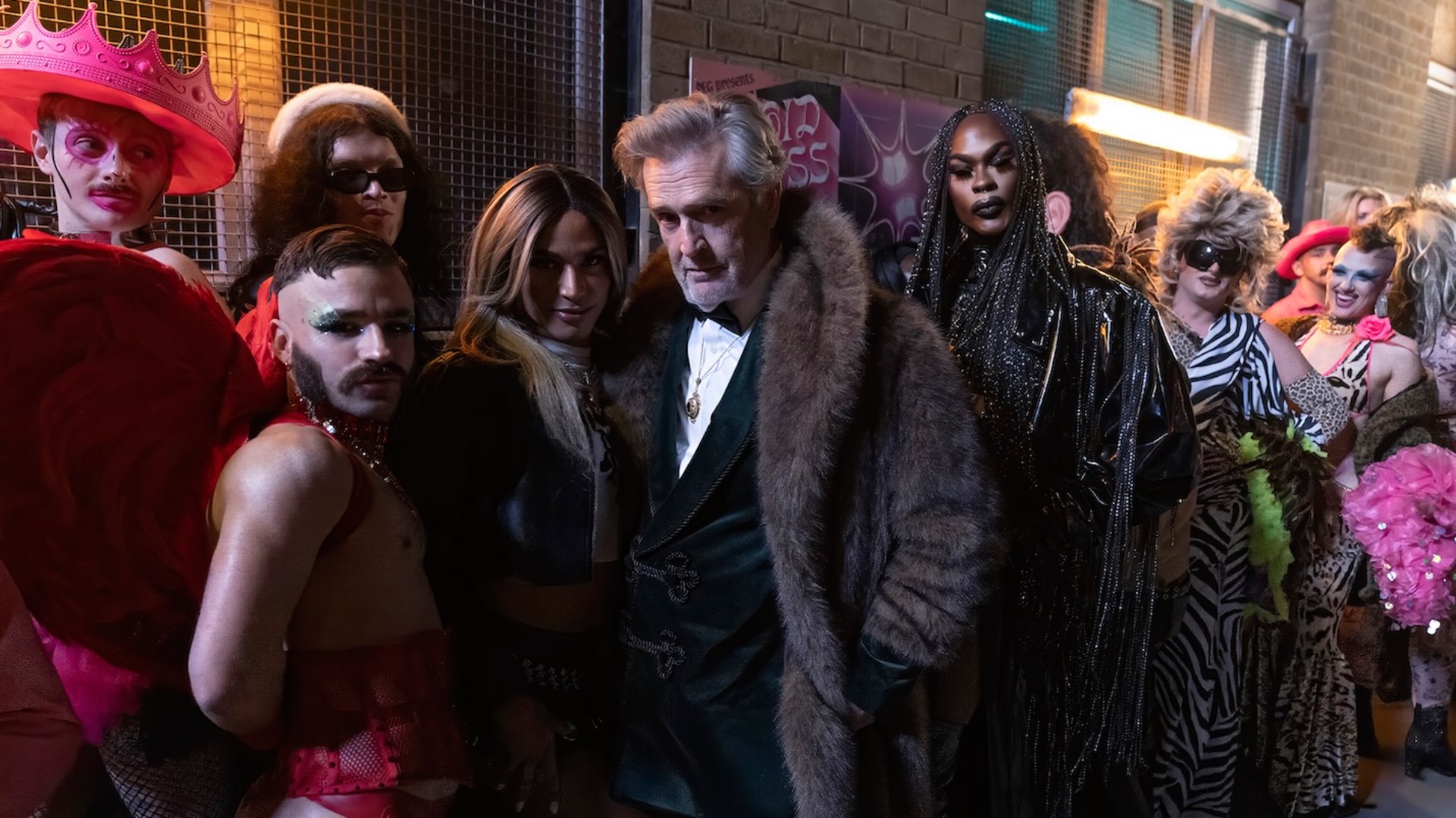 Rupert Everett in Big Mood series 2 in a fur coat surrounded by drag queens