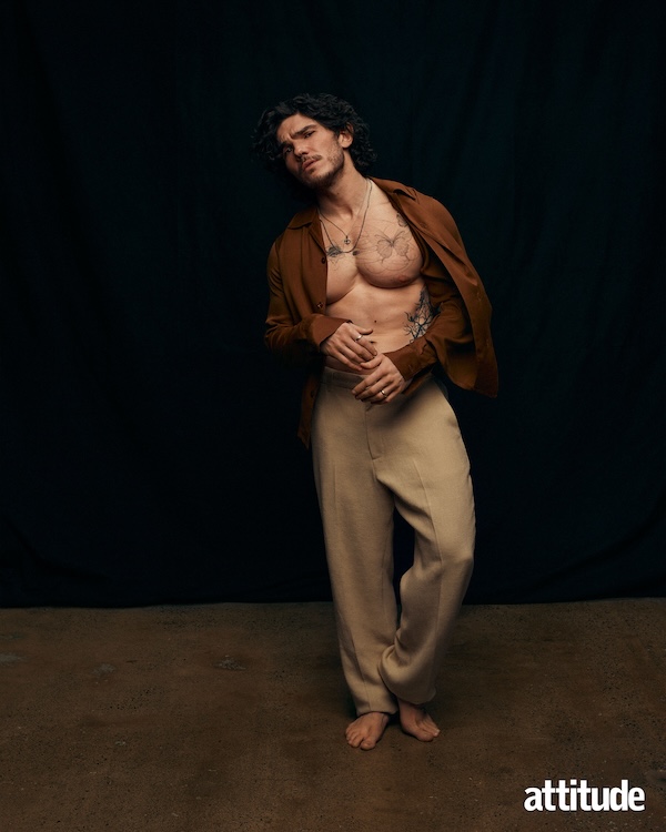 Fre Fee wears a brown open shirt paired with beige trousers.