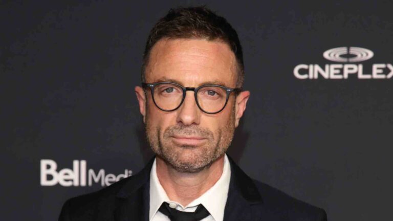 Jacob Tierney in a white shirt and black tie under a black blazer, paired with glasses, on the red carpet