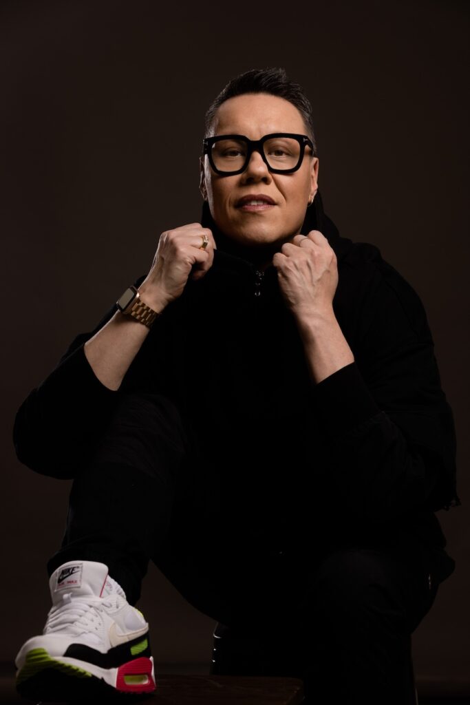 Gok Wan adjusted his black turtleneck jumper while wearing large black glasses