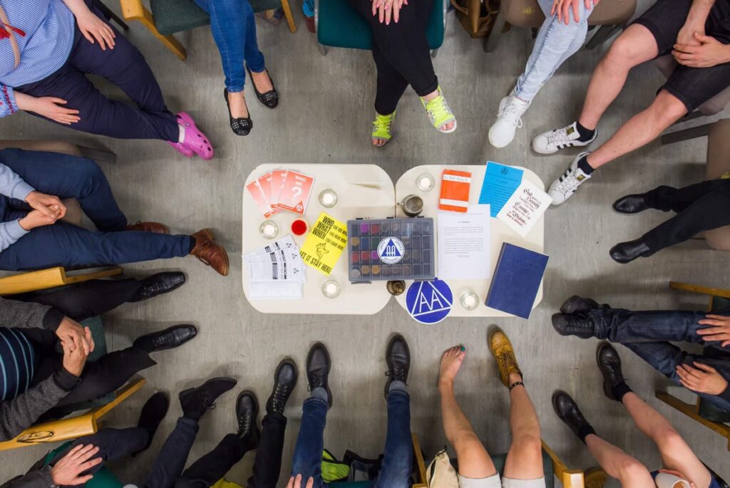 the feet of a group of people attending an lgbt AA meeting, taken from above