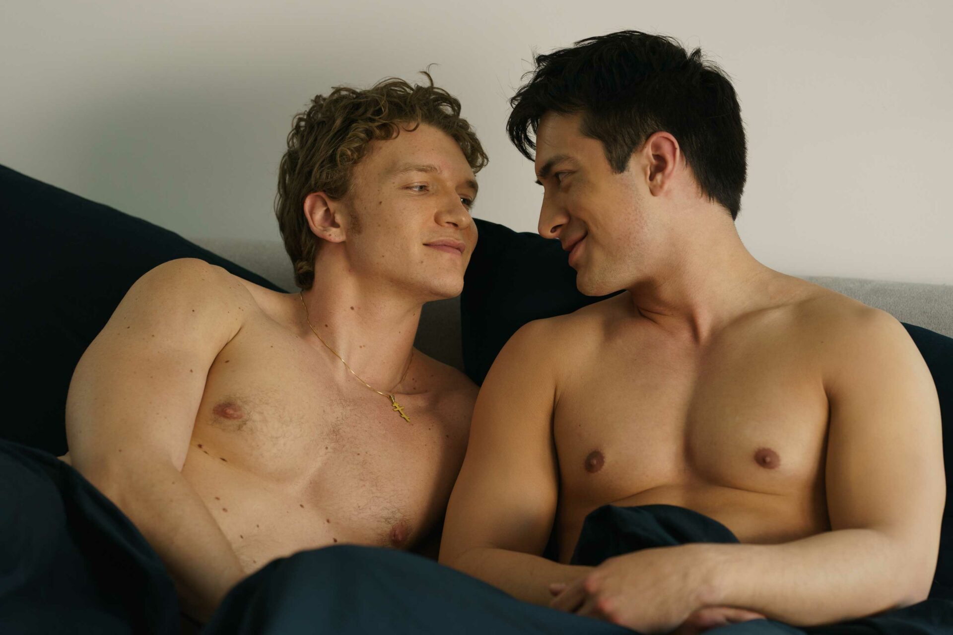 Heated Rivalry stars Shane Hollander (Hudson Williams) and Ilya Rozanov (Connor Storrie) in bed