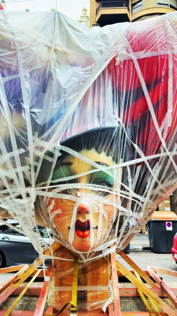 A ninot in the street waiting to be added to a huge fallas 