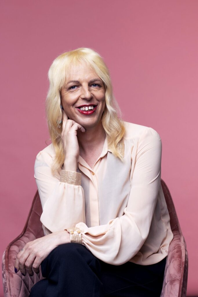 head and shoulders shot of Sarah Savage in white shirt with pink background