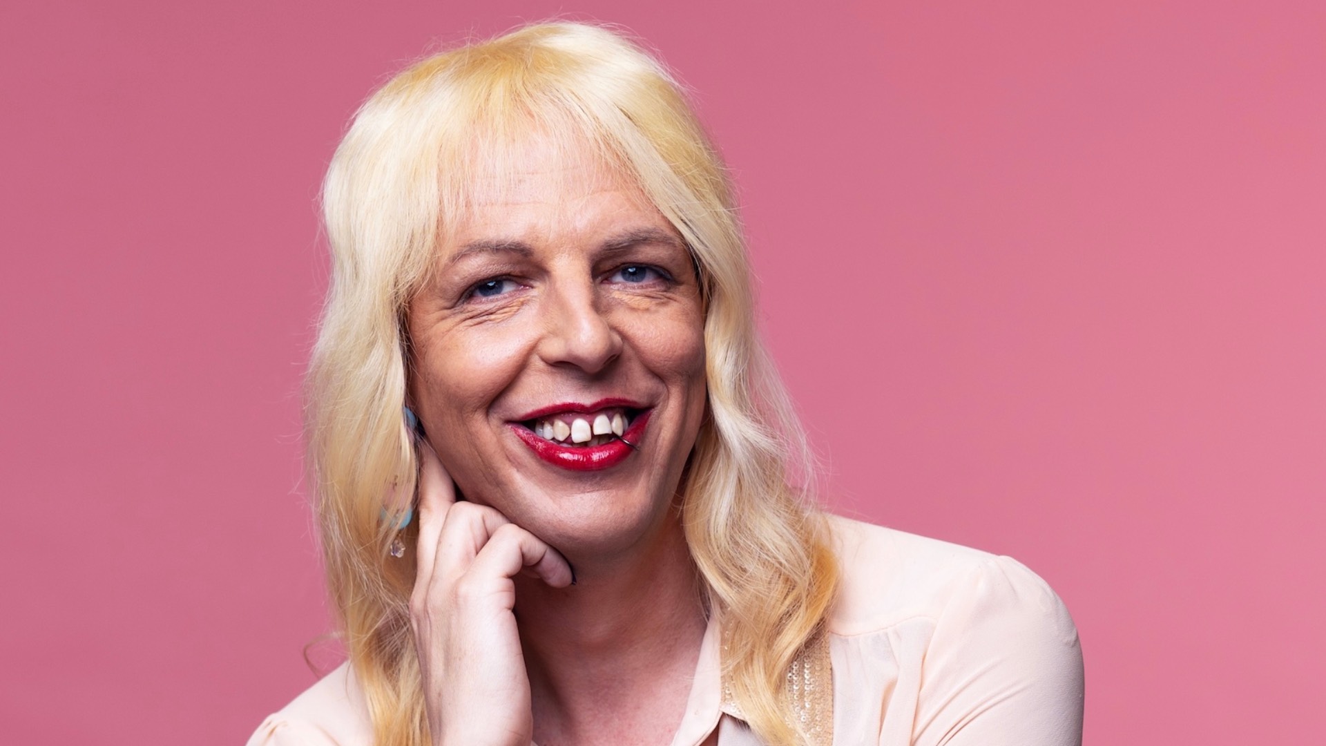head and shoulders shot of Sarah Savage in white shirt with pink background
