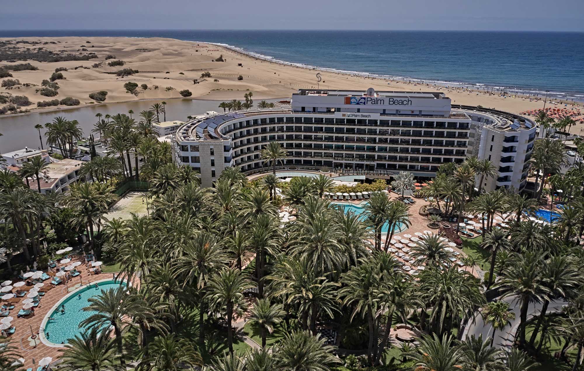 An aerial shot of the Seaside Palm Beach hotel and its grounds with the sandy dunes and sea in the background