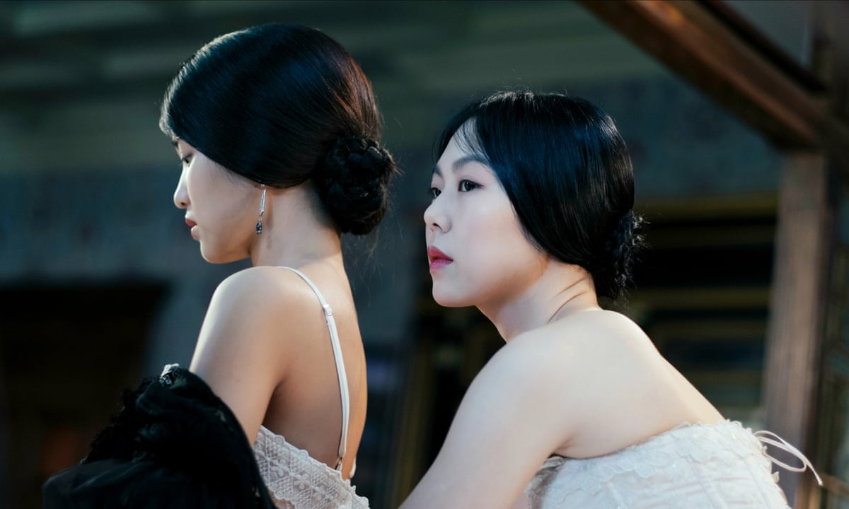 A film still from 2016's The Handmaiden, showing the main female characters from behind, hair up in white tops, with shoulders exposed, one looking to the left
