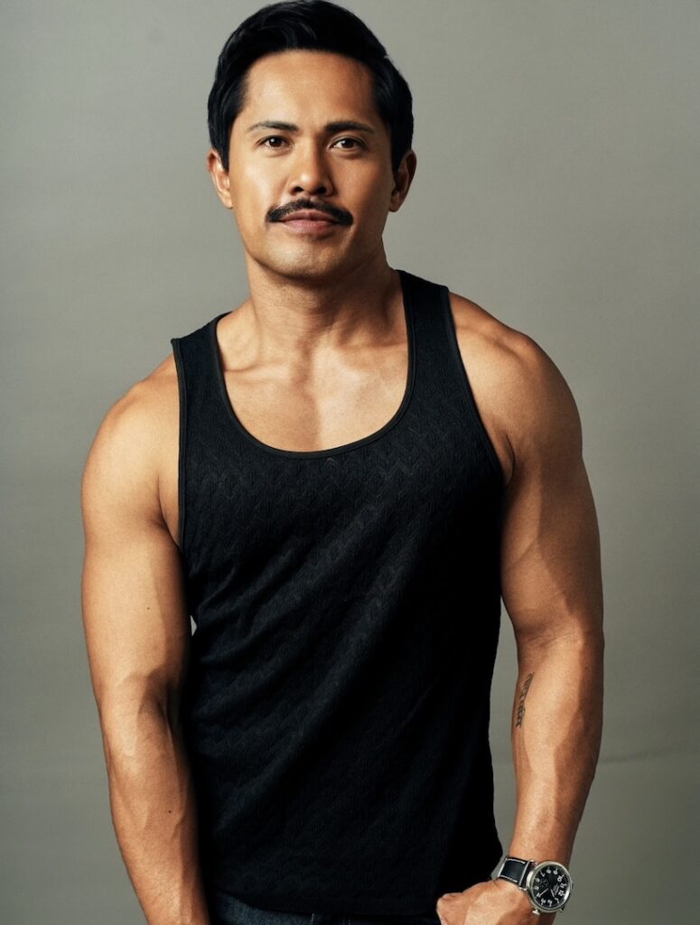 Joel Relampagos in a black vest with his arms down by his side