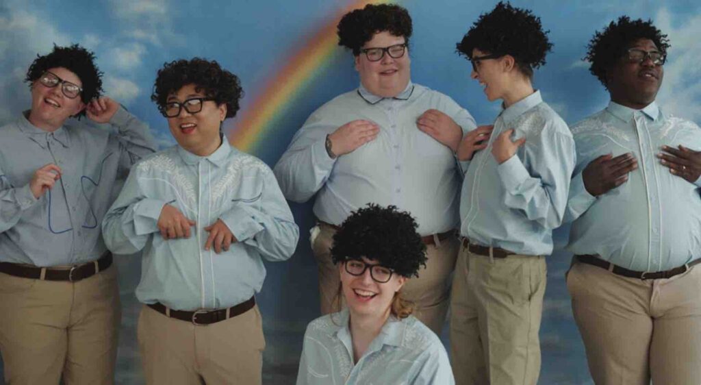 A group of children wearing blue shirts with a rainbow sky behind them
