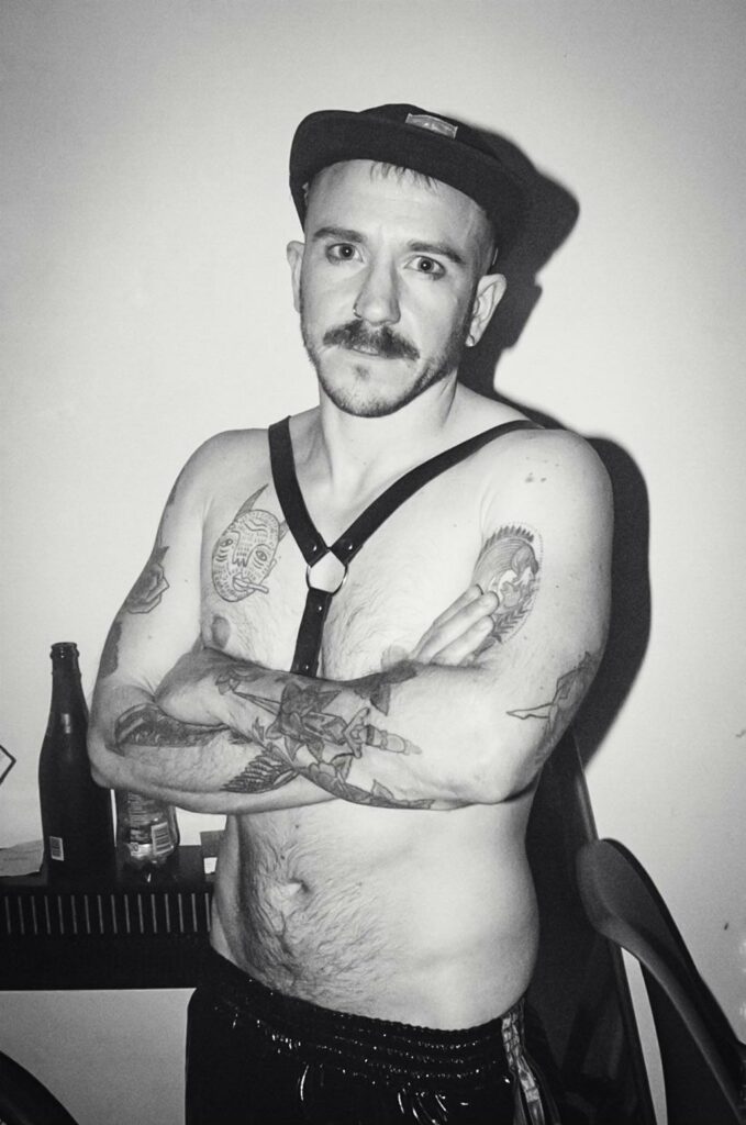 contributor Zach Ellams toppess in a black hat and harness 