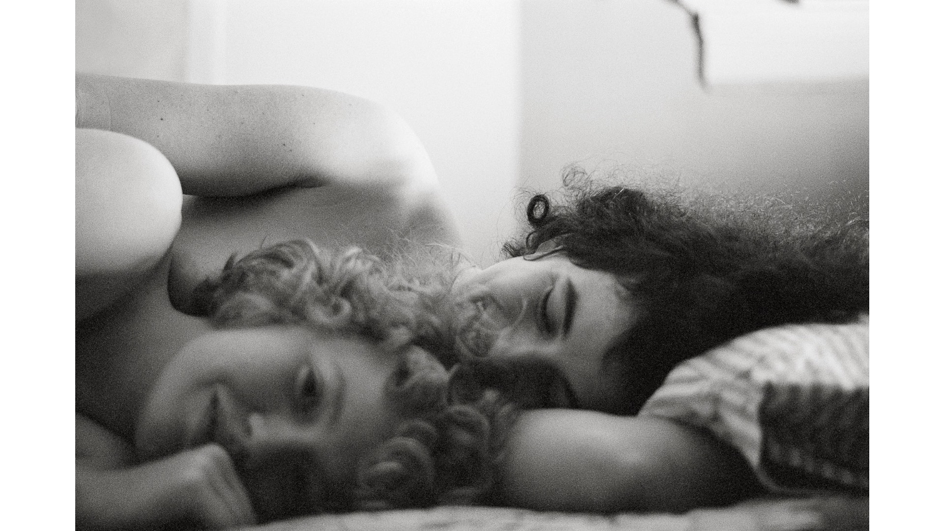 A photography of two curly haired women lying in a bed – Donna Gottschalk  Self-portrait with JEB, E. 9th Street, New York, 1970 Courtesy of the artist and Marcelle Alix, Paris © Donna Gottschalk