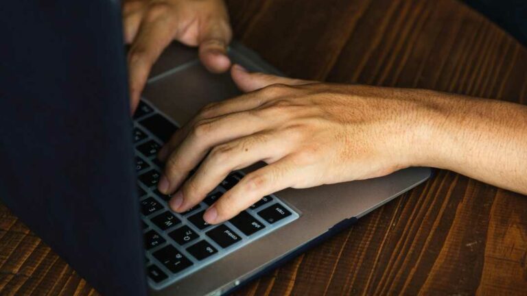 Close shot of a man's hands typing on a laptop