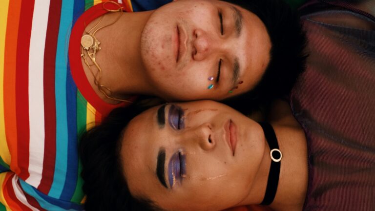 Two asian men laying down side by side, one of them crying