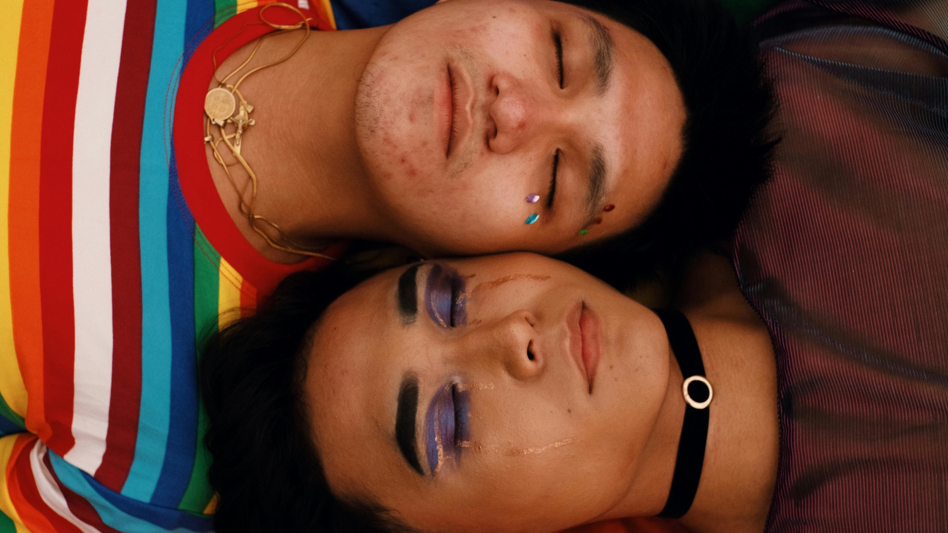 Two asian men laying down side by side, one of them crying