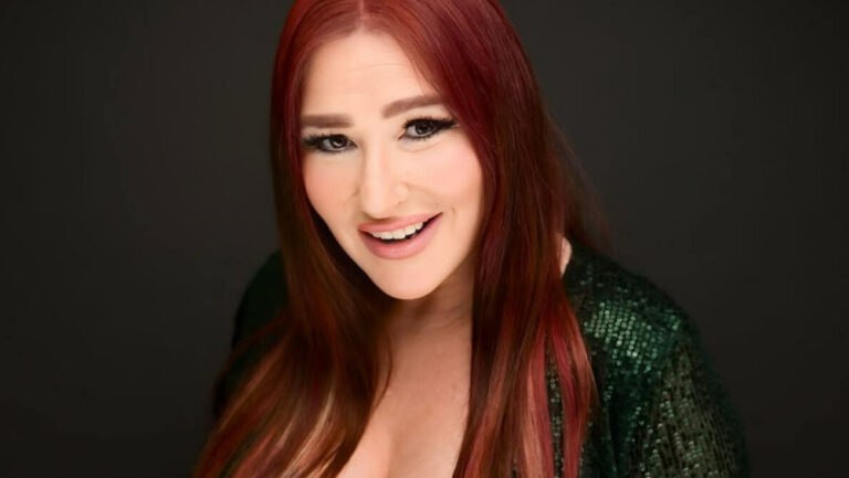 80s singer Tiffany with red hair and a green top smiling into the camera