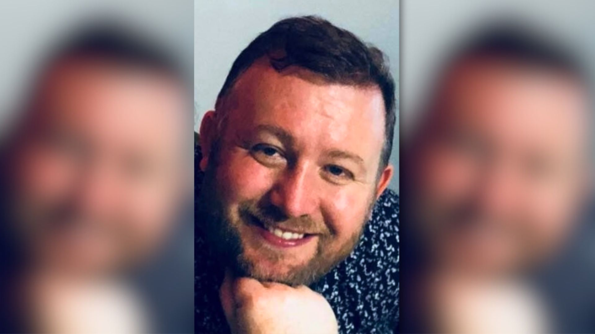 Portrait shot of a smiling man with brown hair and a beard