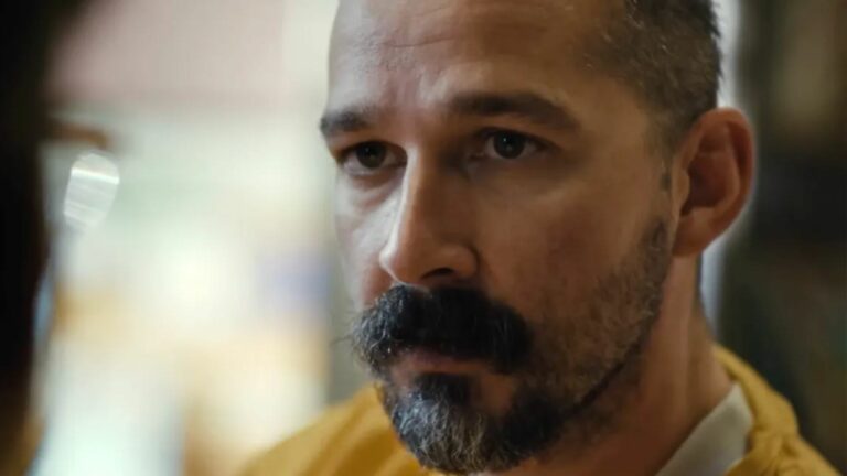 Shia LaBeouf, wearing a yellow top and sporting a bushy moustache