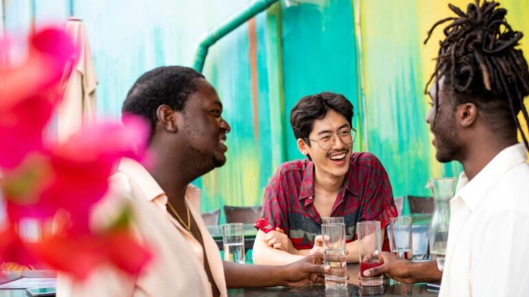 Three friends chatting outdoors in front of a colourful mural in Wynwood, Miami