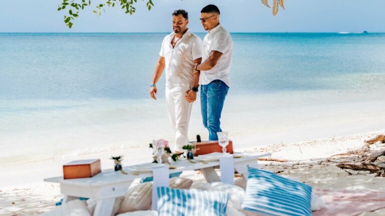 A gay couple walking on a beach in Aruba