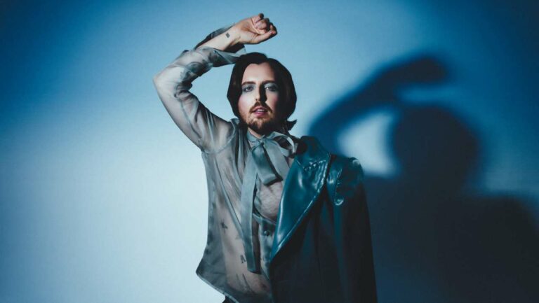 Jhart in a blue suit against a blue backdrop