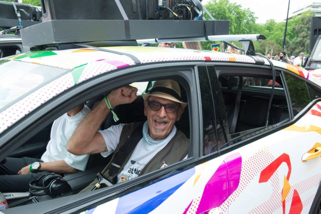 Jonathan Blake sitting in the passenger seat of a Peugeot New 408 with a colourful Pride wrap at the  2026 Pride in London parade.