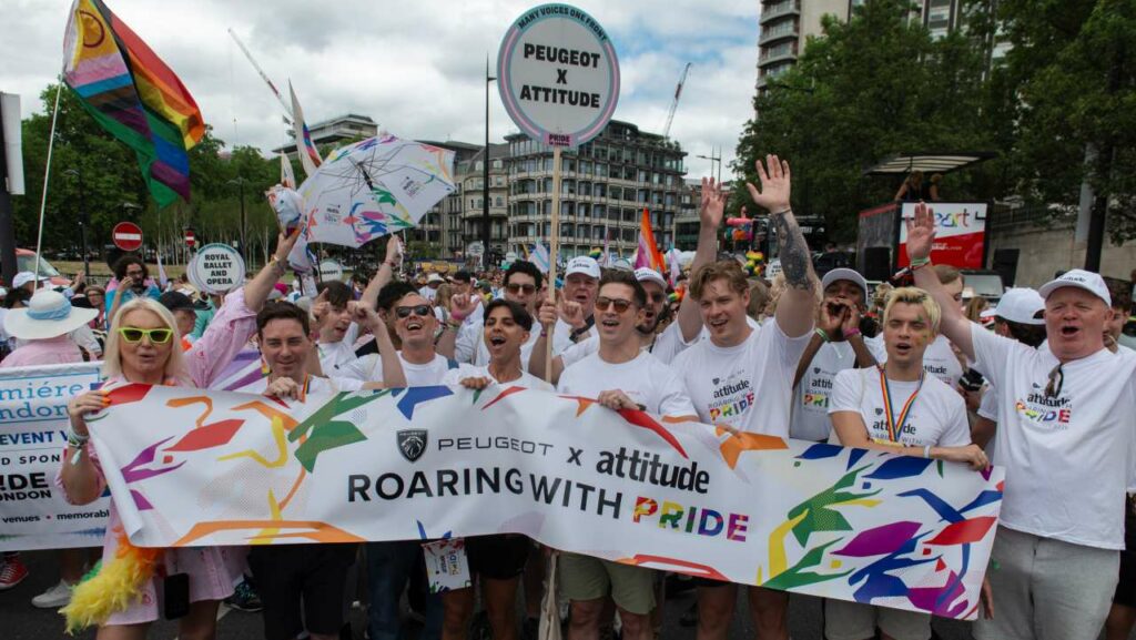 Carl Cashman, Jason Patel, India Willoughby at the 2026 Pride in London Parade holding a PEUGEOT x Attitude banner