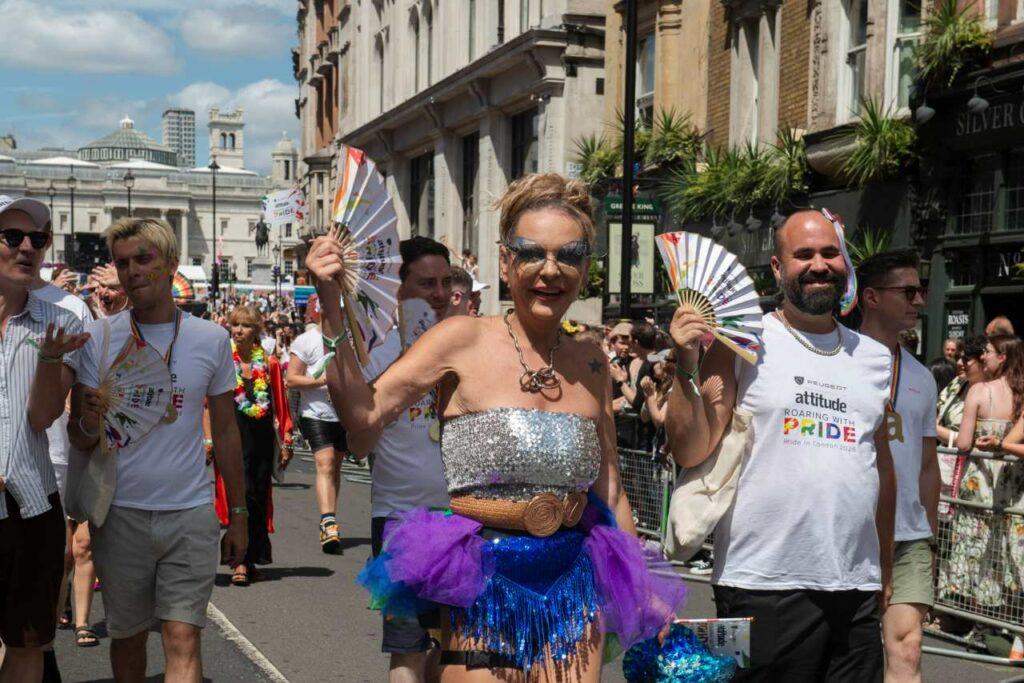 2026 Pride Awards winners marching in the Pride in London parade, with a participant in a silver and purple outfit holding a hand fan in the centre
