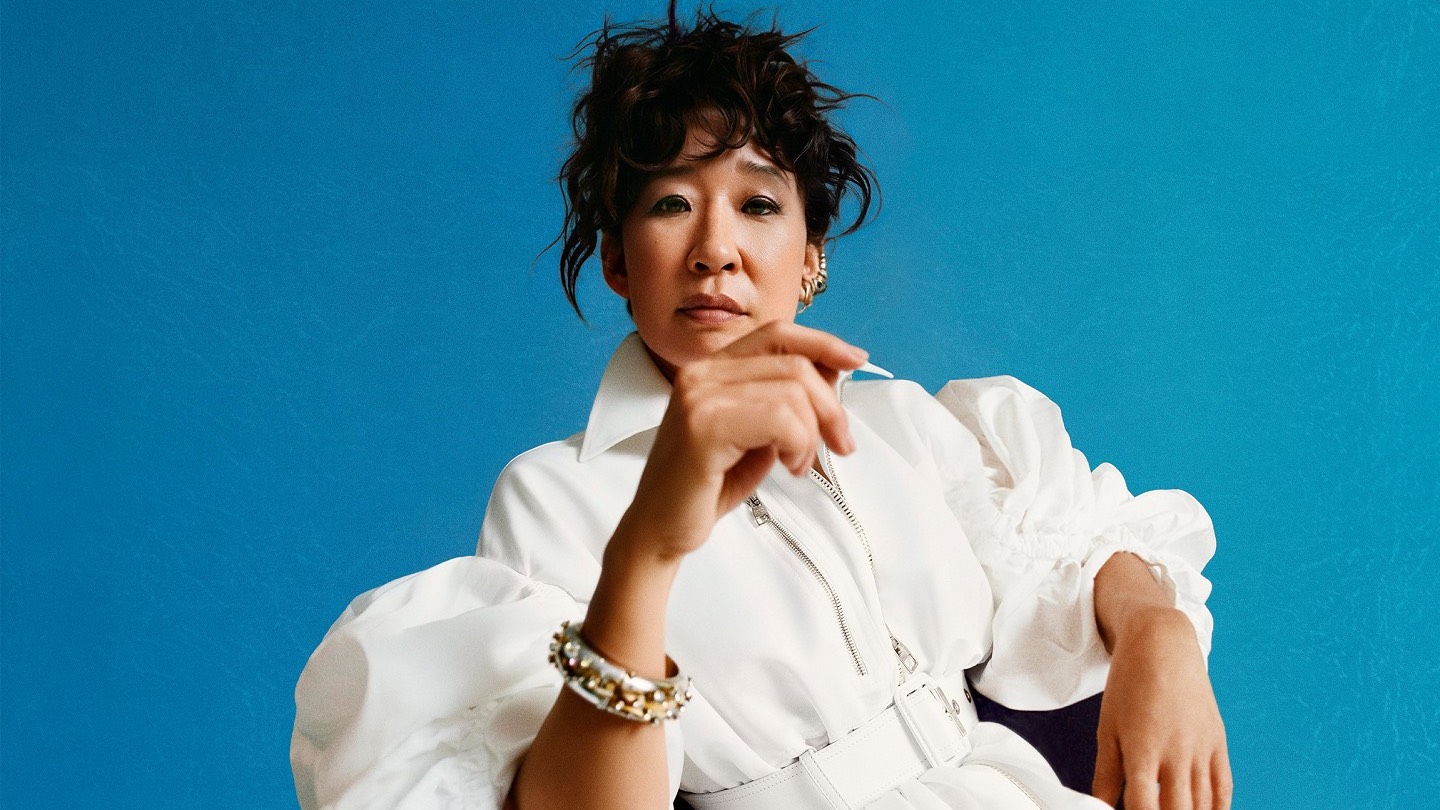 Sandra Oh in a press shot for The Misanthrope, in a white blouse against a blue backdrop (Image: National Theatre)