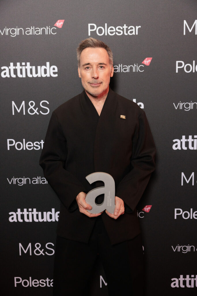 David Furnish in black holding his award