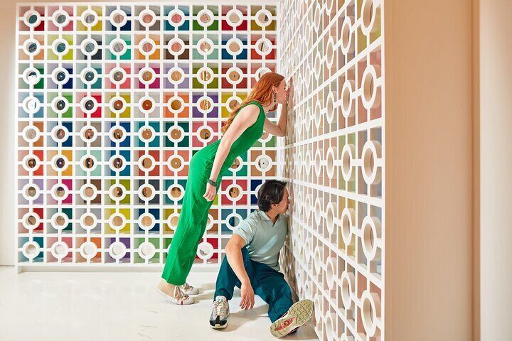 A couple peering through a wall at the Color Factory in Chicago