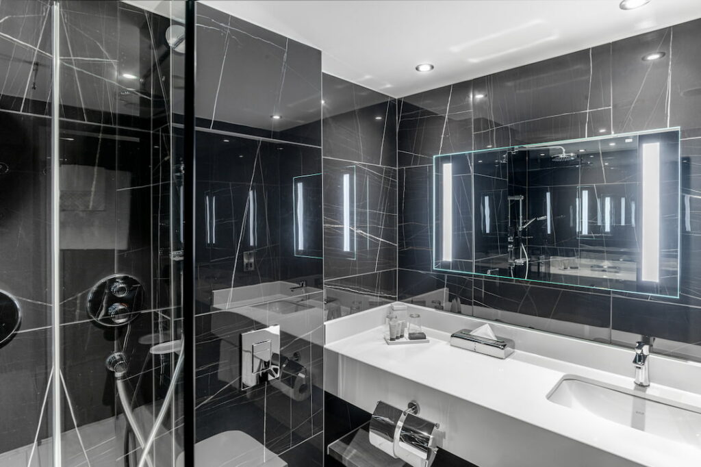 A standard double room bathroom with black marble tiles and Balmain toiletries