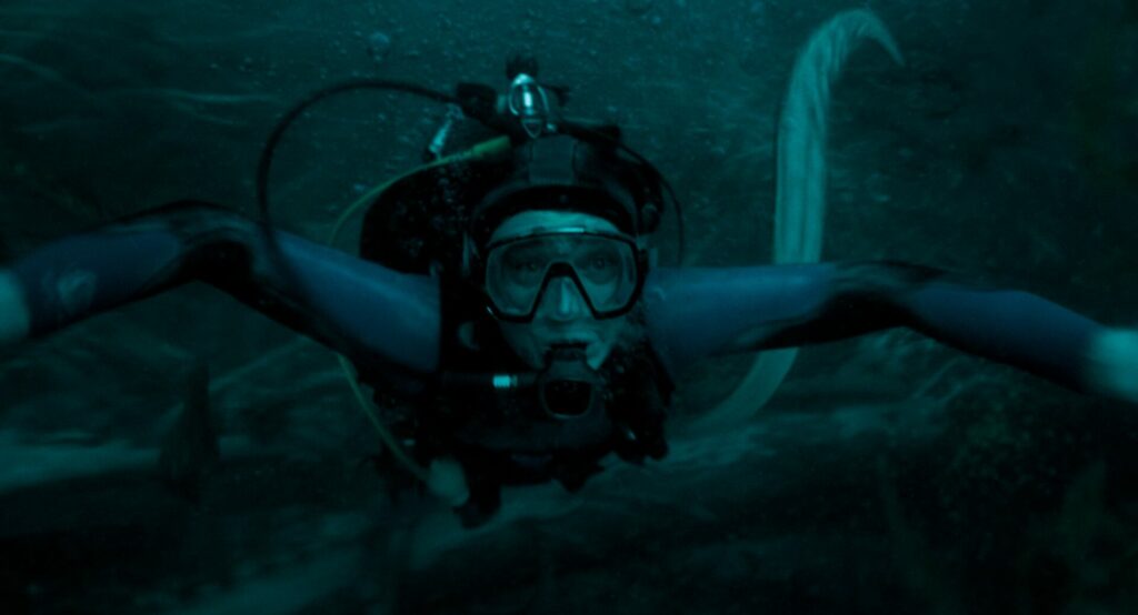 Austin Abrams in Whalefall, diving with octopus behind him (Image: 20th Century Studios)
